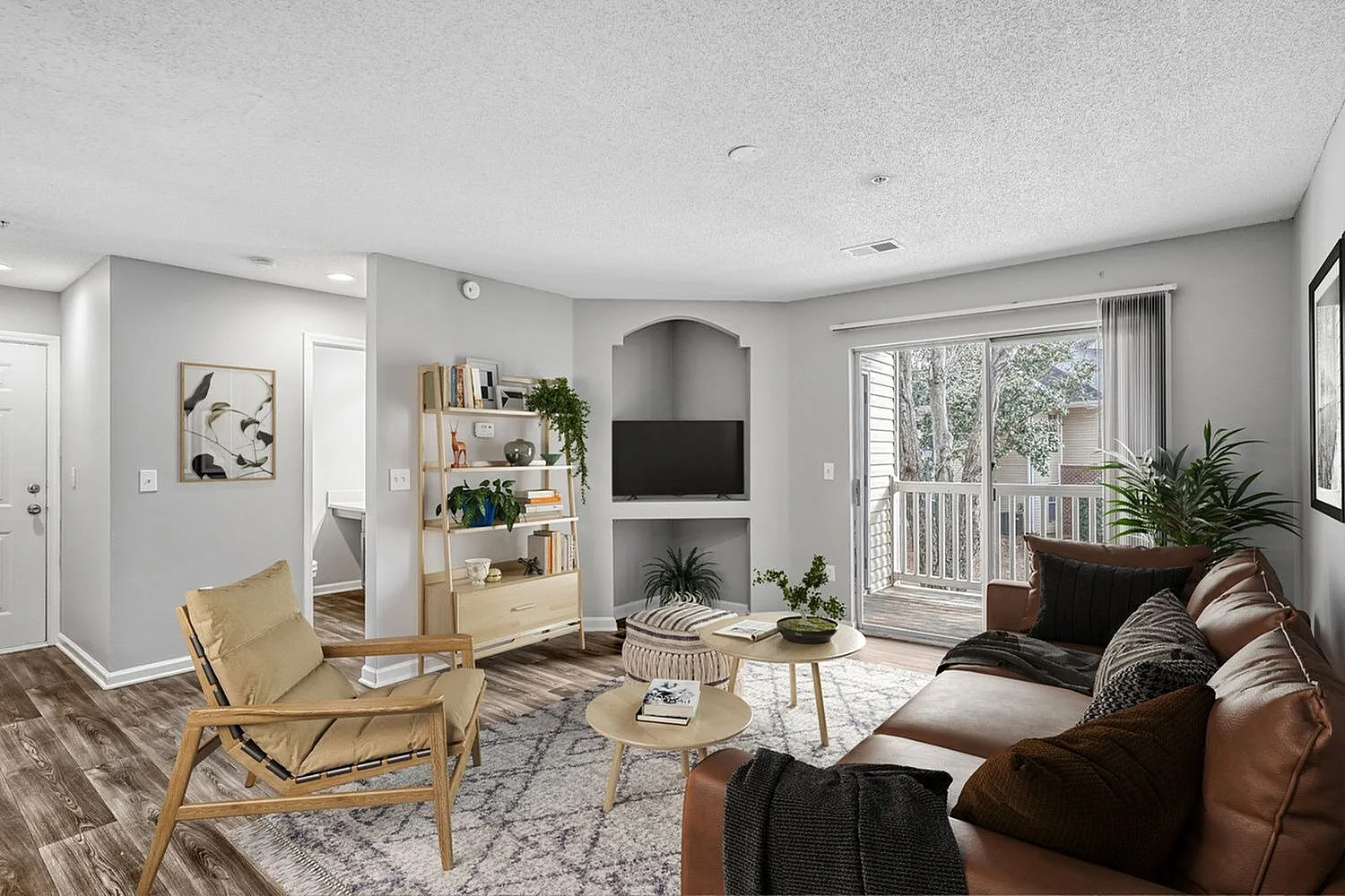 Living room with wood-style plank flooring, leather sofa, fireplace, built-in shelving