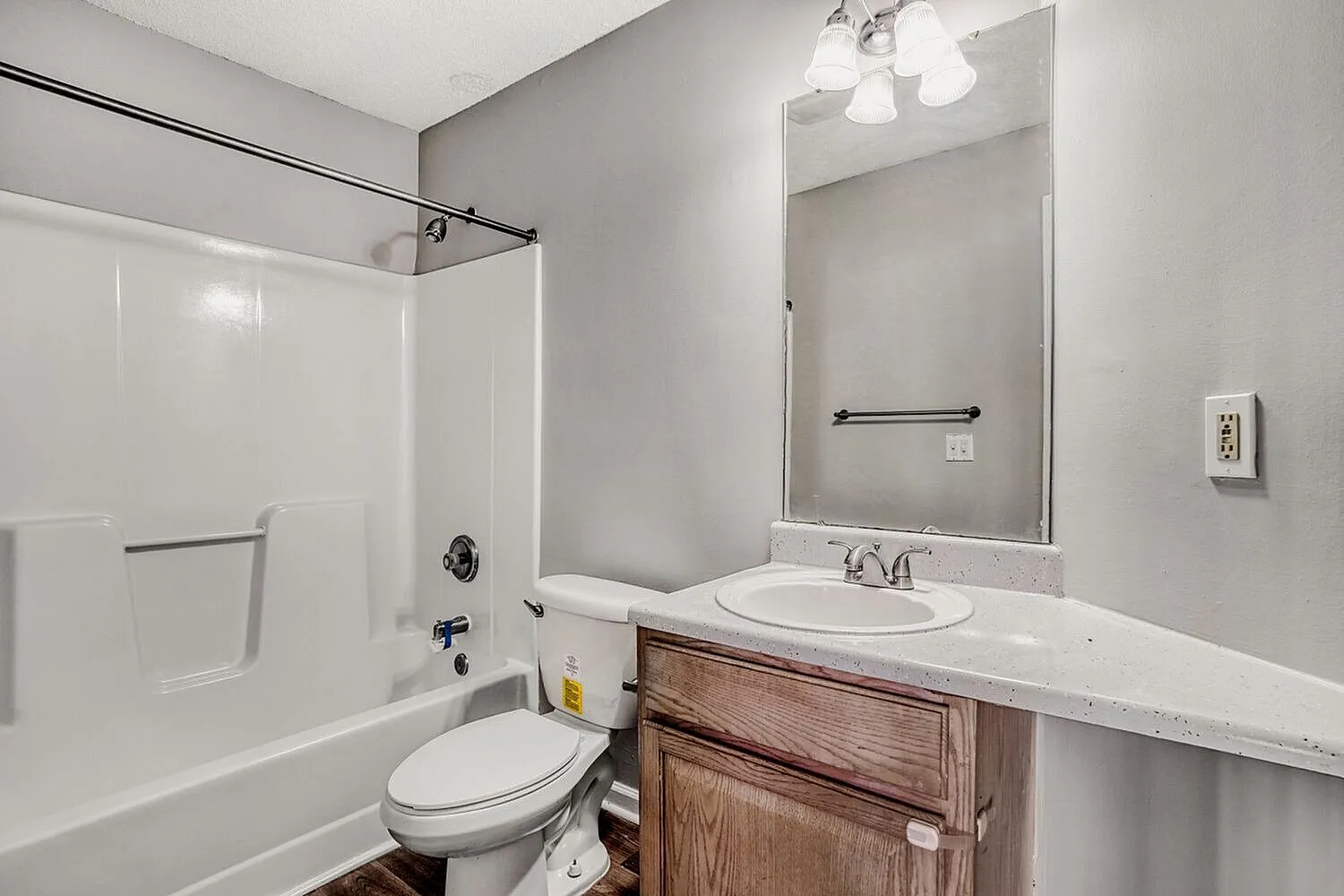 Bathroom, wood-style vanity cabinet, white quartz countertop, large mirror with lighting