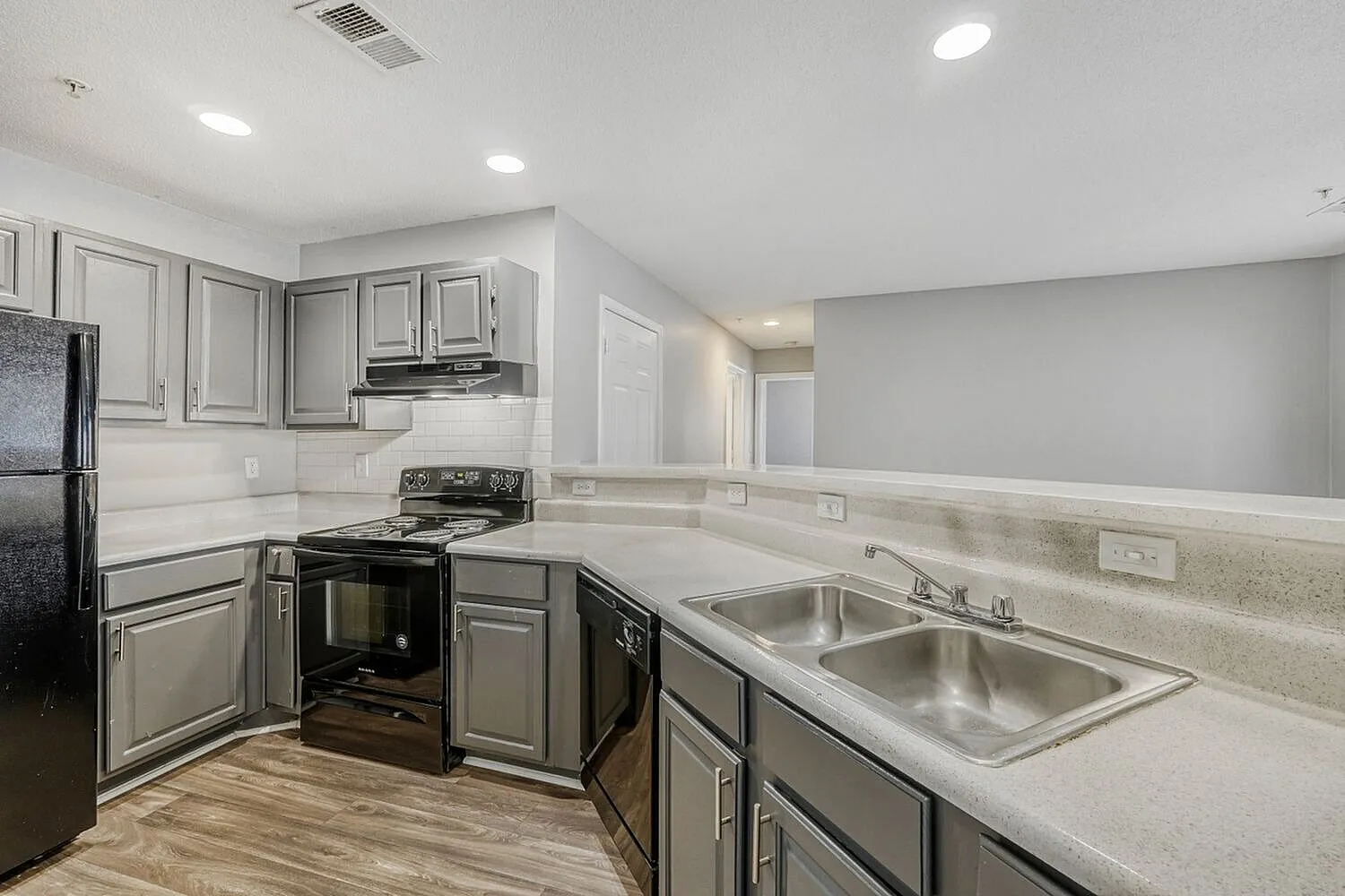 Kitchen, light gray shaker cabinetry, quartz countertops, stainless steel sink, wood-style plank flooring