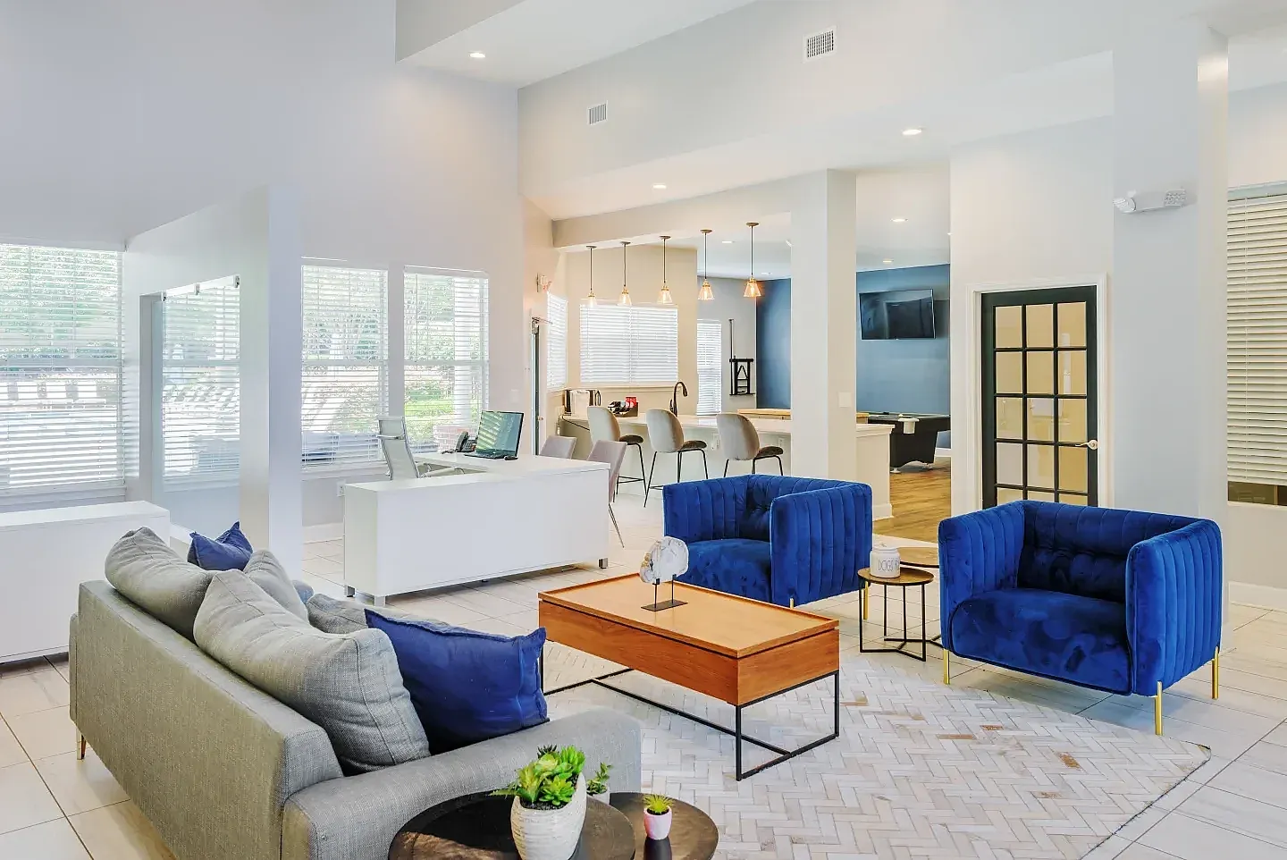 Lobby and lounge area, gray upholstered sofa, blue accent chairs, wood-style plank flooring