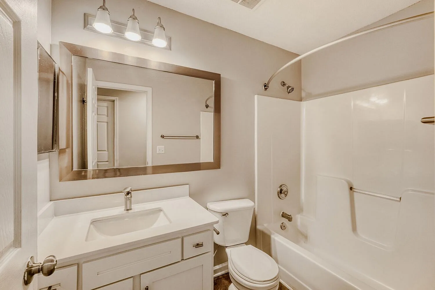 Bathroom with white vanity, rectangular mirror, ceiling lights, toilet, white tile shower enclosure