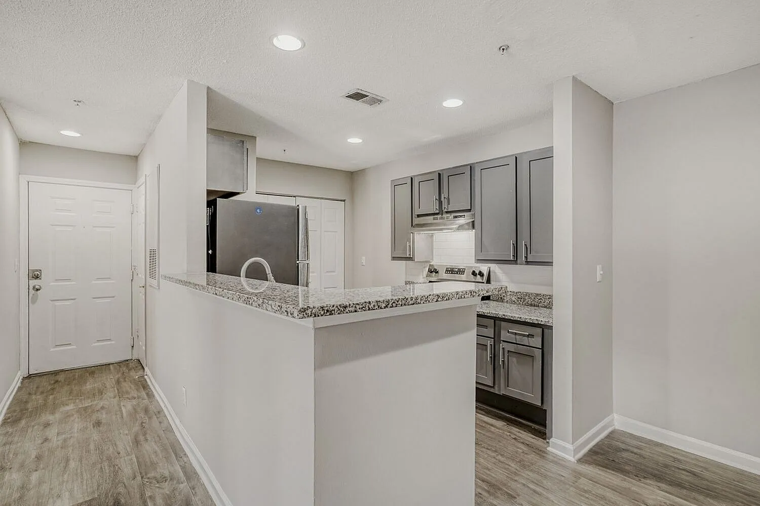 Kitchen, gray cabinetry, speckled countertops, stainless appliances, wood-style plank flooring