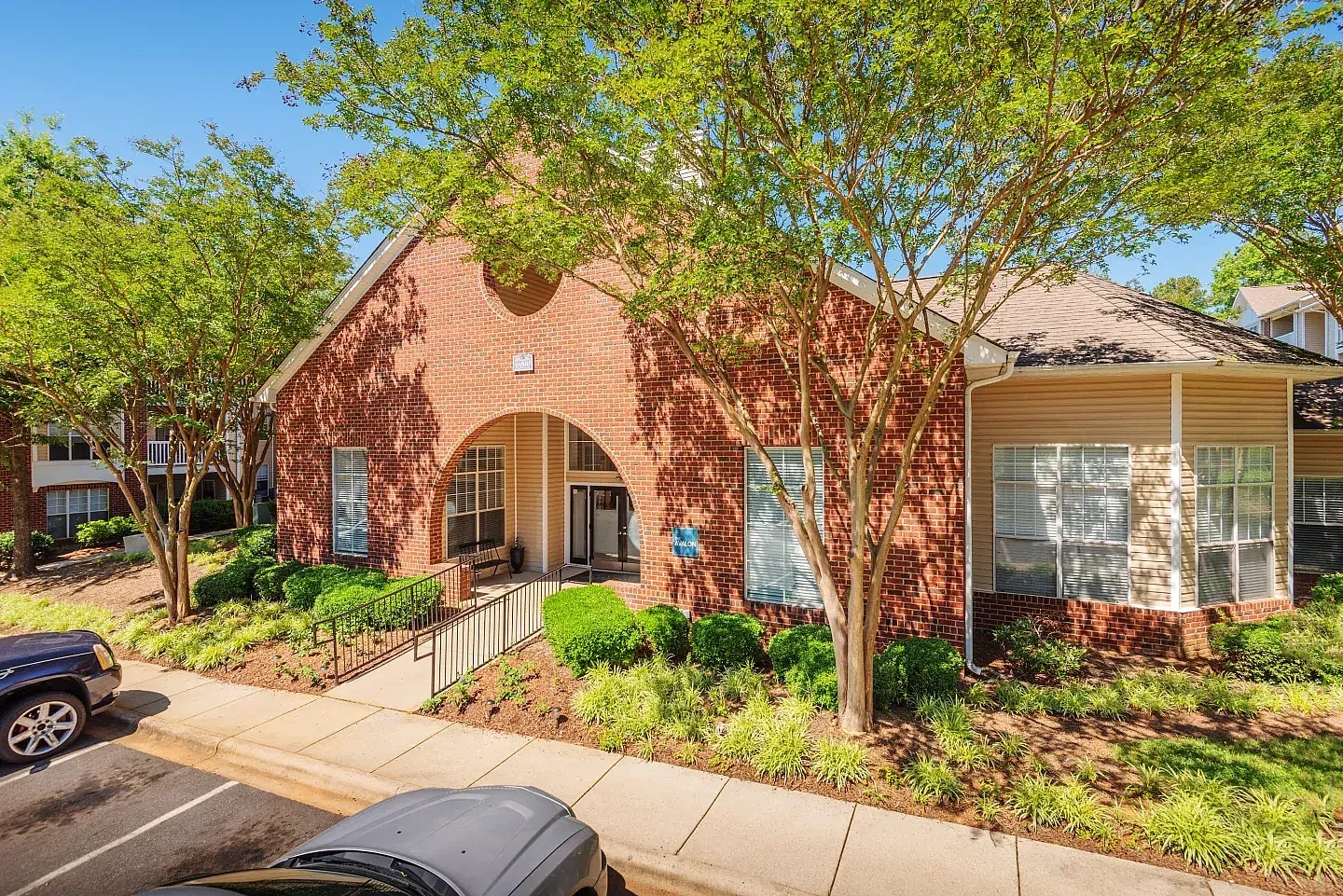 Red brick building with arched entryway, landscaped grounds with mature trees, Charlotte