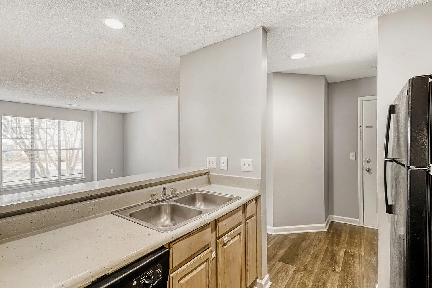 Kitchen with double sink, light wood cabinetry, stainless appliances, wood-style plank flooring