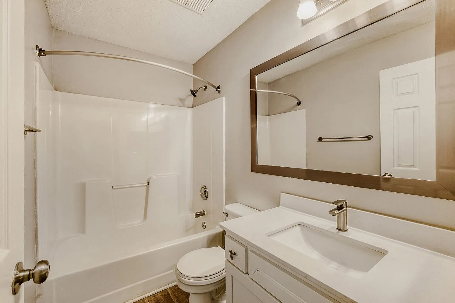 Primary bathroom, white vanity sink, framed mirror, toilet, shower tub combo