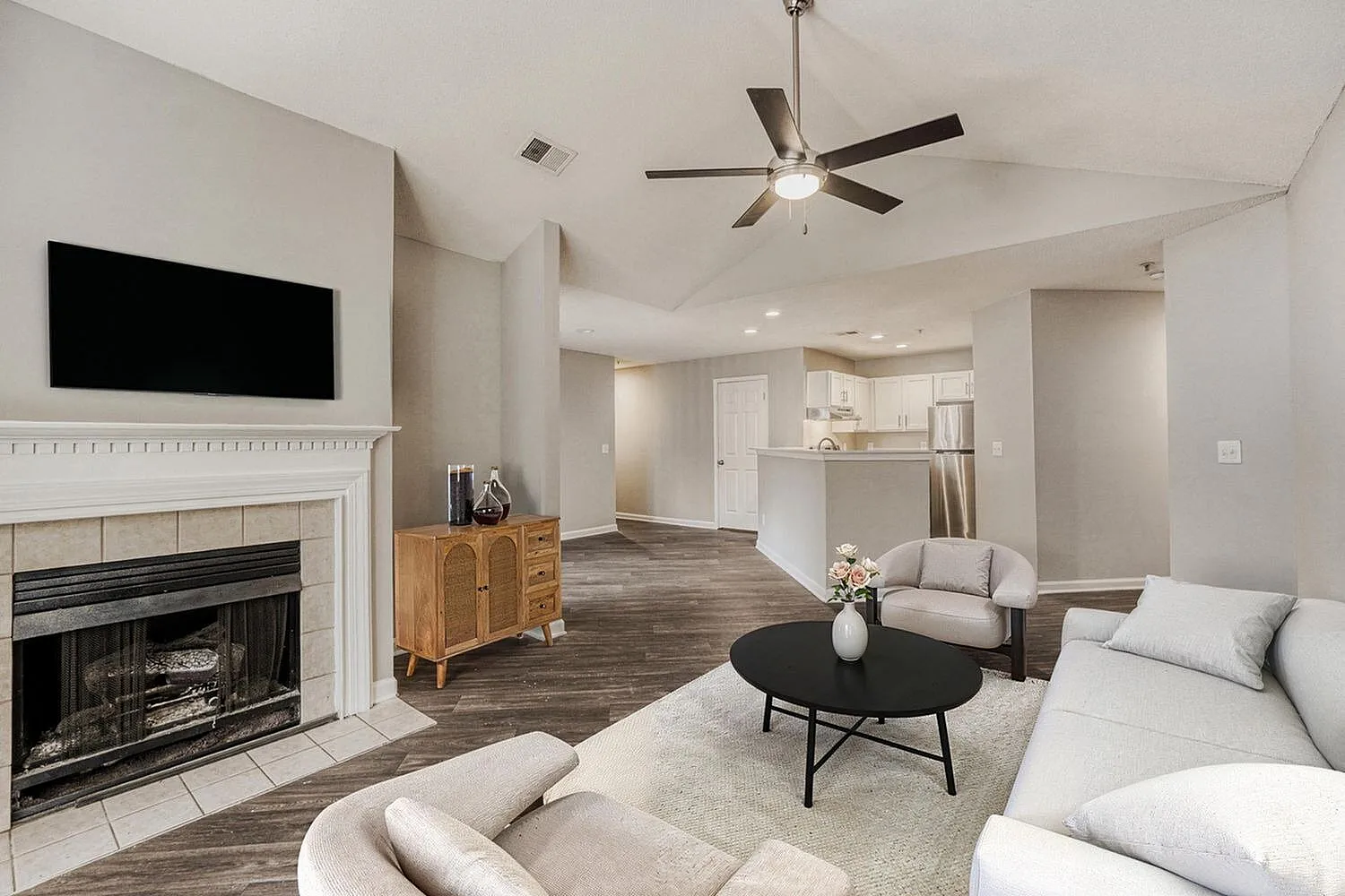 Living room, wood-style plank flooring, fireplace with tile surround, ceiling fan, open floor plan