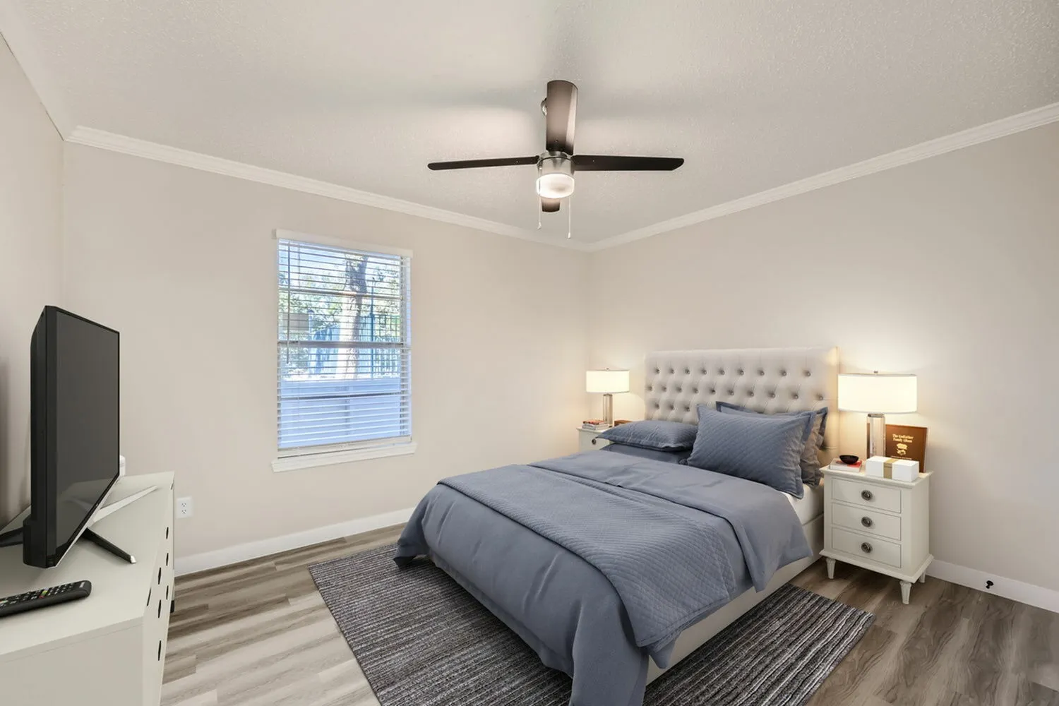 Primary bedroom, wood-style plank flooring, upholstered headboard, ceiling fan, bedside lighting