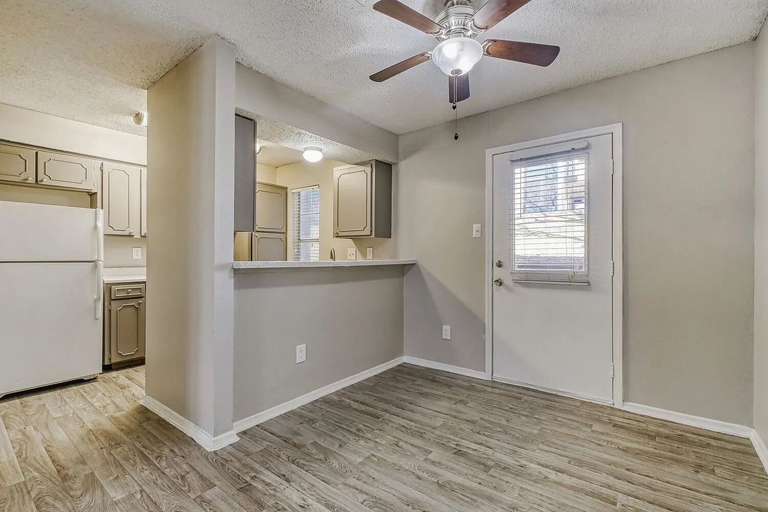Kitchen and dining area, wood-style plank flooring, ceiling fan, glass door entry
