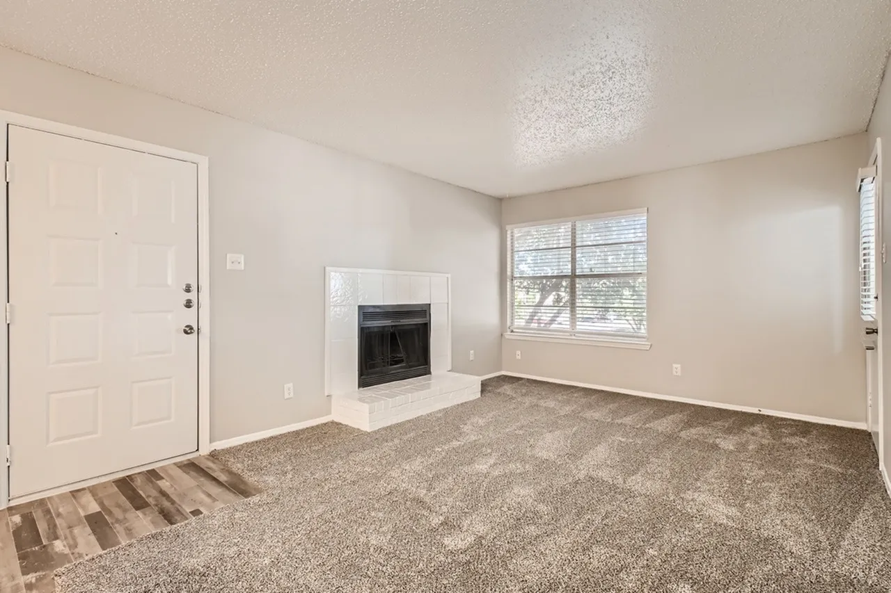 Living room, carpet flooring, fireplace, windows with blinds, entry door