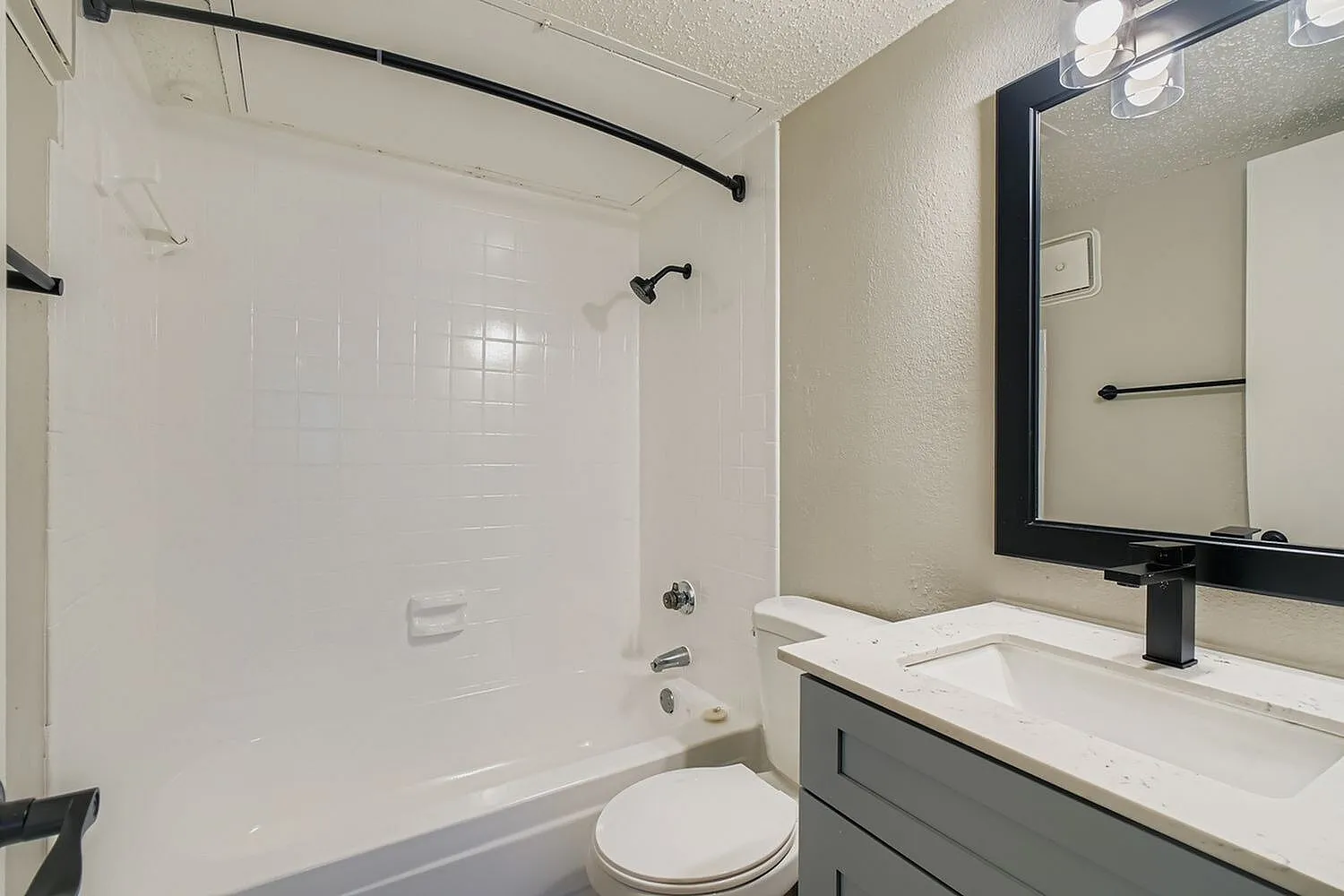 Bathroom, white subway tile shower surround, dark vanity cabinetry, black framed mirror