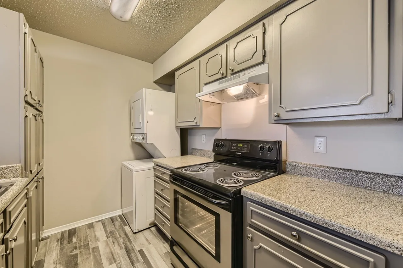 Kitchen, cream cabinetry, speckled countertops, black electric range, wood-style plank flooring