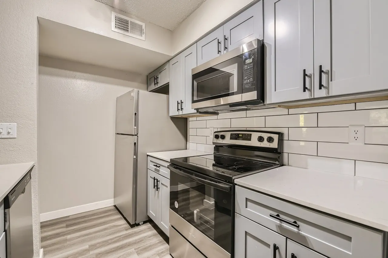 Kitchen, gray shaker cabinetry, quartz countertops, stainless steel appliances, subway tile backsplash, wood-style plank flooring