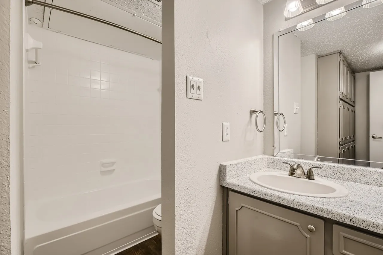Bathroom, dual sink vanity, speckled gray countertops, framed mirror, tile flooring