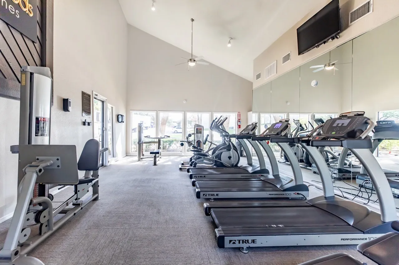 Fitness center, treadmills, elliptical machines, wood-style plank flooring, glass windows