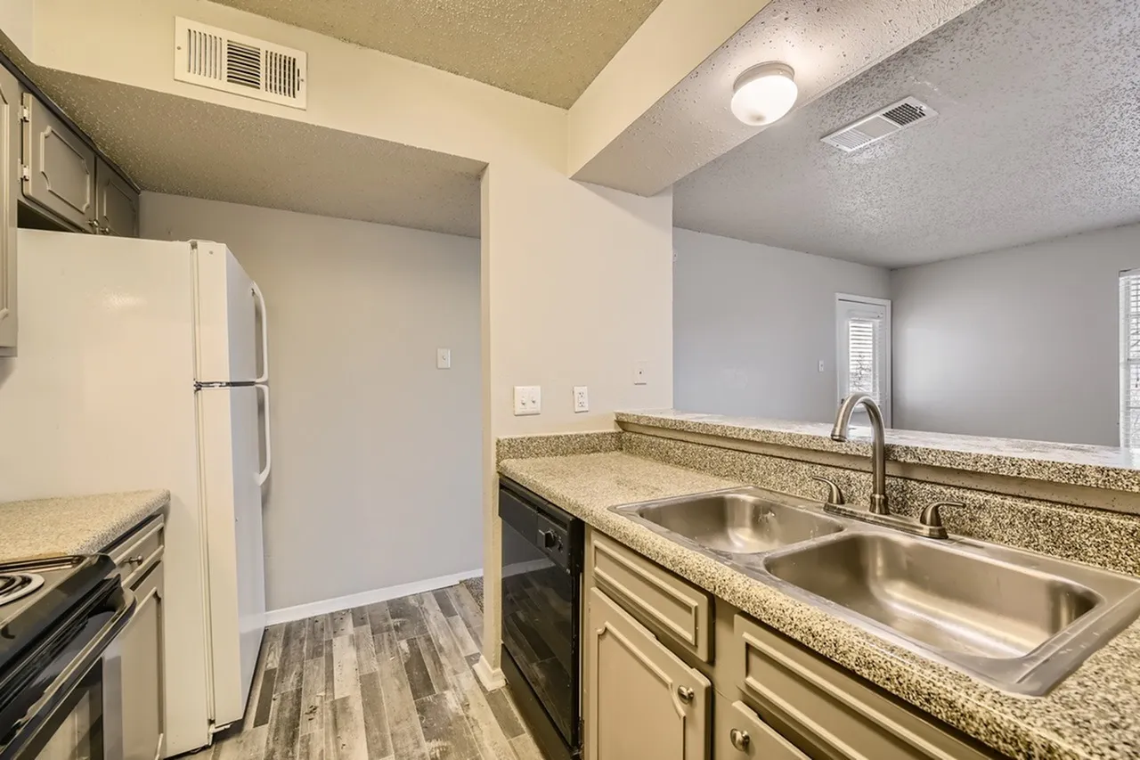 Kitchen with white refrigerator, black range, wood-style plank flooring, bathroom with dual sink vanity, granite countertops, stainless steel fixtures