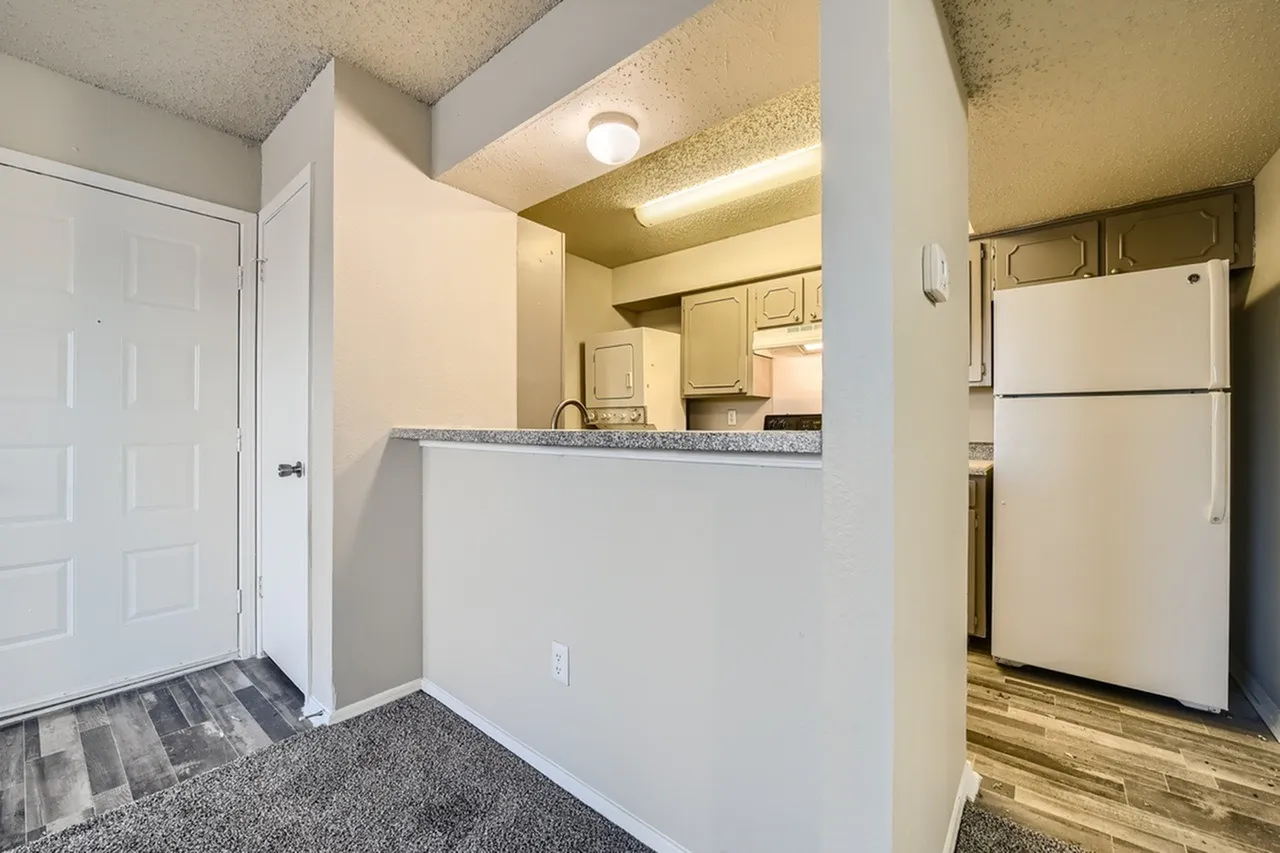 Kitchen with gray countertops, white cabinetry, stainless appliances, wood-style plank flooring, entry door