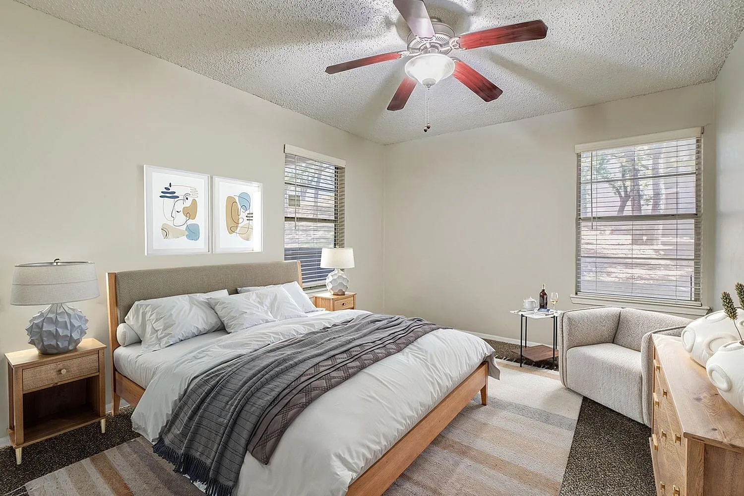 Primary bedroom, wood-style plank flooring, wood bed frame, ceiling fan with light, windows with blinds