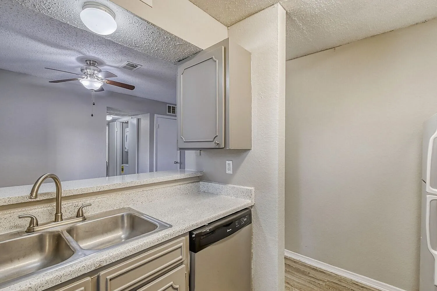 Kitchen, light quartz countertops, stainless steel sink, cream cabinetry, large mirror