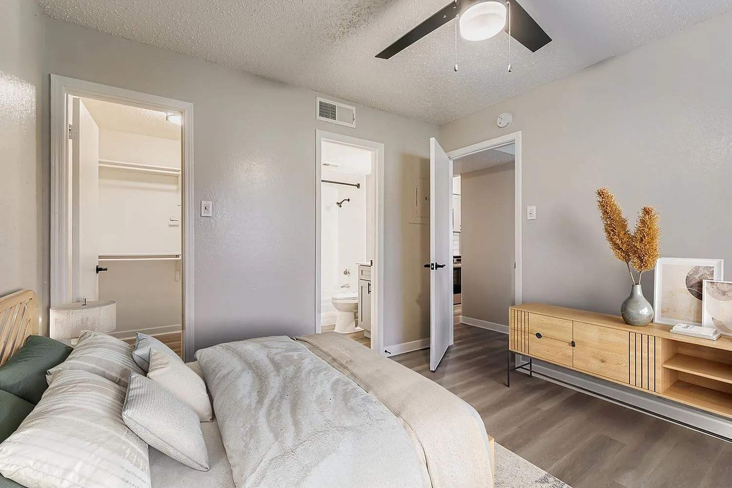 Primary bedroom, wood-style plank flooring, ceiling fan, ensuite bathroom visible