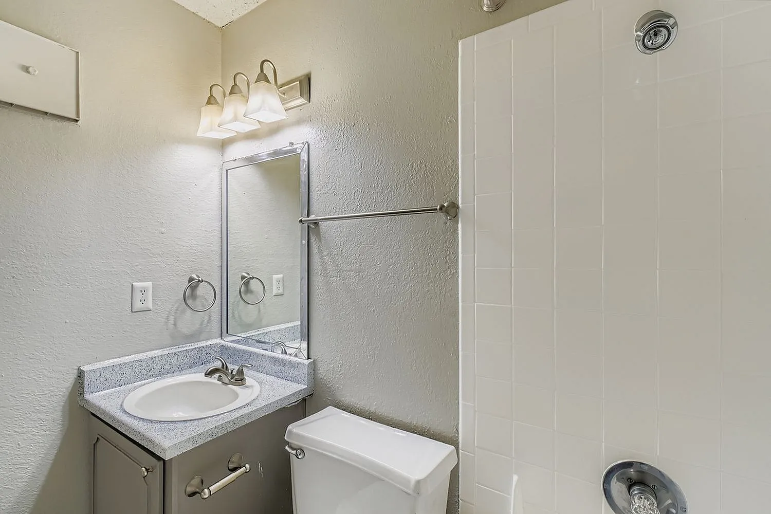 Bathroom, white round sink, gray countertop, mirrored vanity, frameless shower enclosure