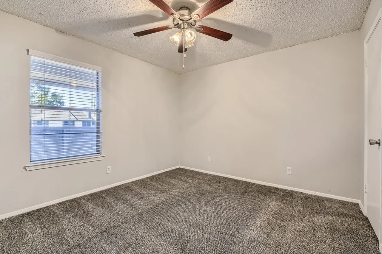 Bedroom, gray carpet flooring, ceiling fan with lights, window with blinds