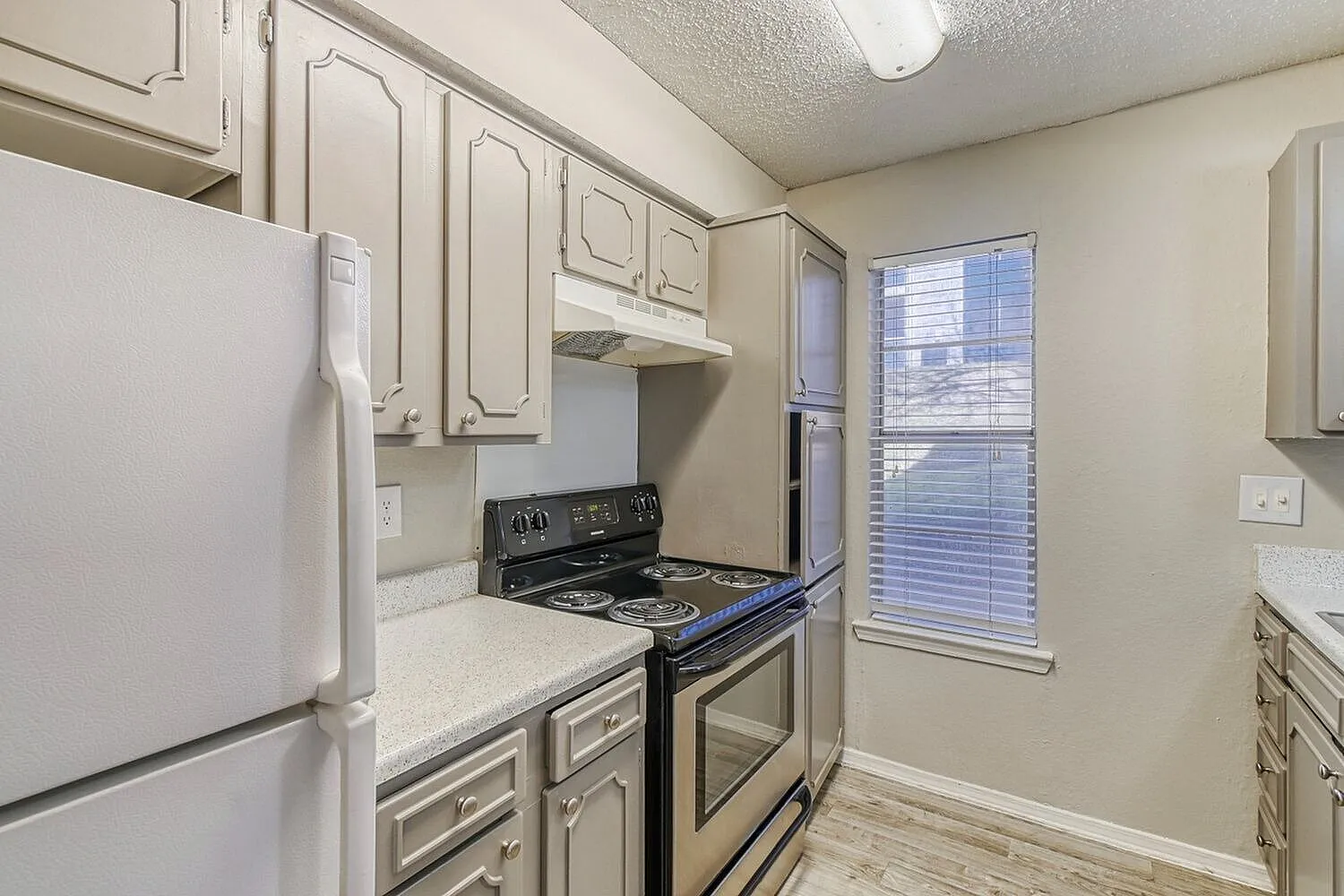 Kitchen, white cabinetry, quartz countertops, gas range, stainless oven, wood-style plank flooring