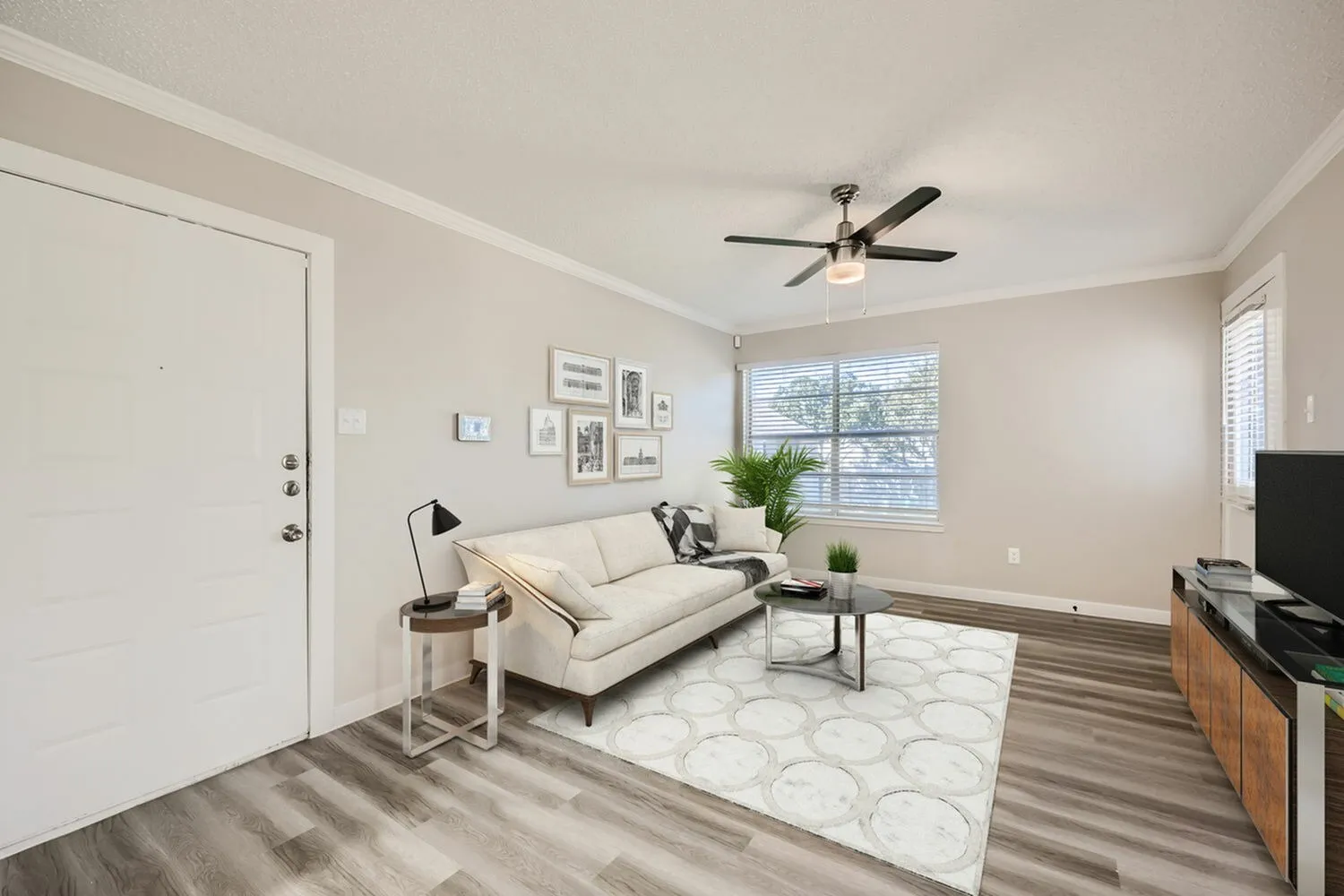 Living room, cream upholstered sofa, wood-style plank flooring, ceiling fan, large windows
