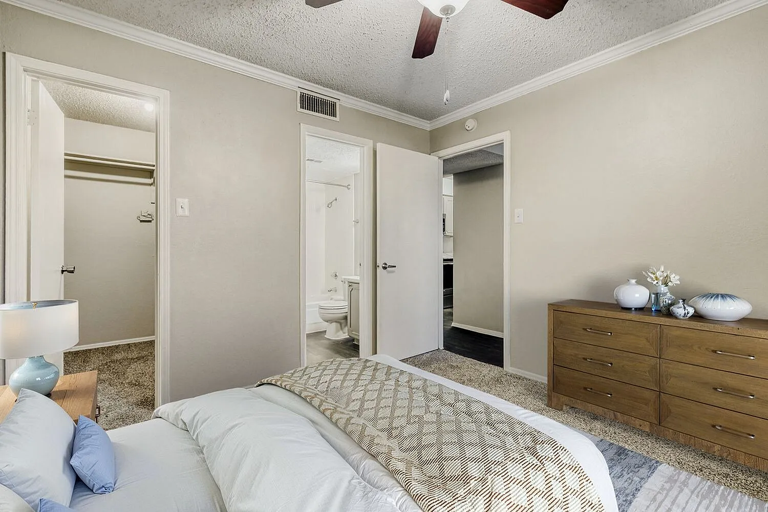 Primary bedroom, wood-style plank flooring, wood dresser, ensuite bathroom and walk-in closet