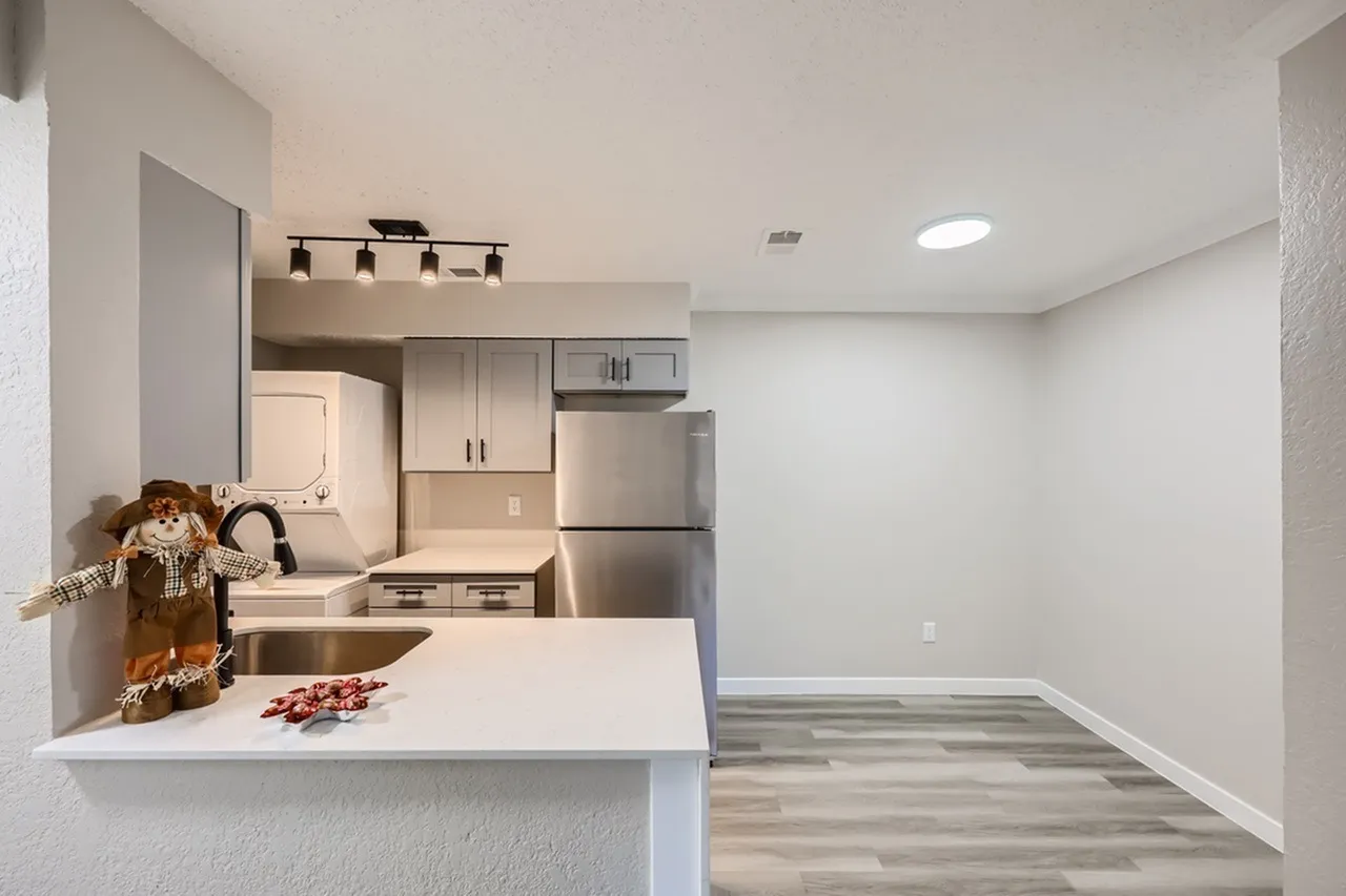 Kitchen, white island with countertop seating, gray cabinetry, stainless steel appliances, wood-style plank flooring