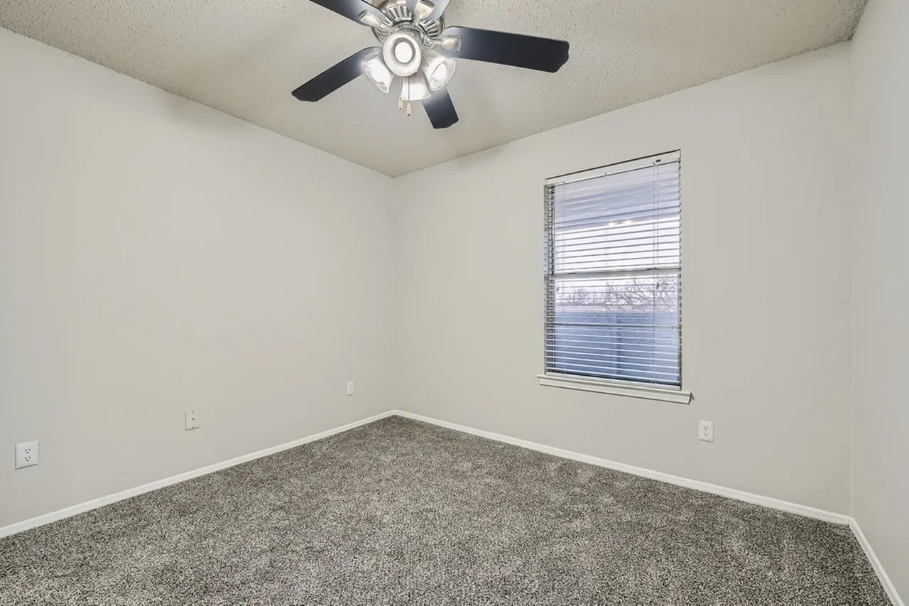 Bedroom, gray carpet flooring, ceiling fan with light, window with blinds