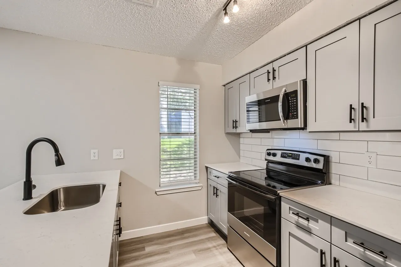 Kitchen, white shaker cabinetry, white subway tile backsplash, stainless appliances, wood-style plank flooring
