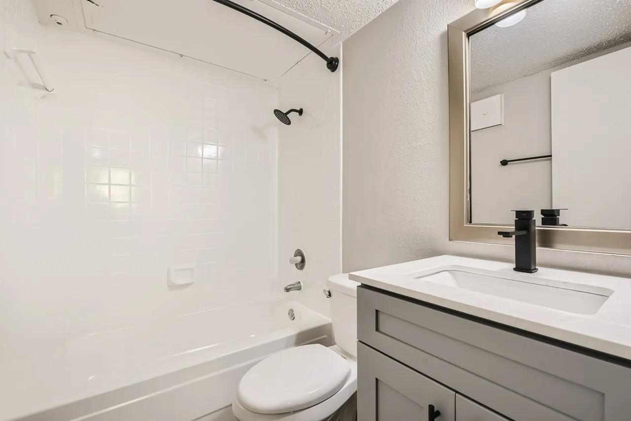 Bathroom, white subway tile shower surround, gray vanity cabinetry, white quartz countertop, framed mirror