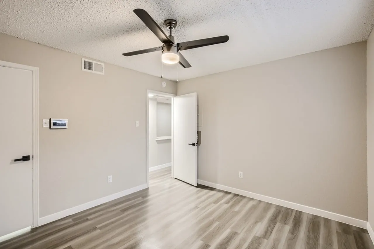 Bedroom, wood-style plank flooring, ceiling fan, white closet door, beige walls