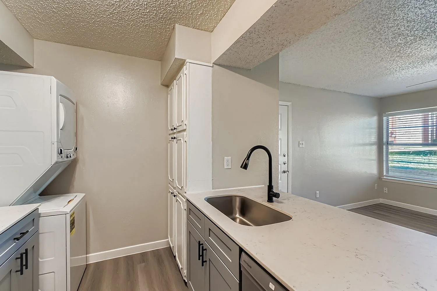 Kitchen, white shaker cabinetry, quartz countertops, stainless sink, black faucet, wood-style plank flooring