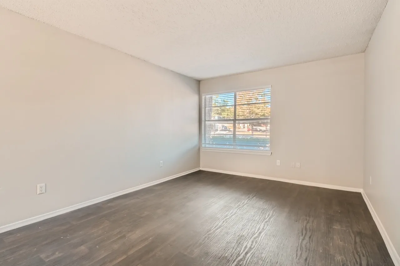 Bedroom, wood-style plank flooring, large window with blinds, white walls and ceiling