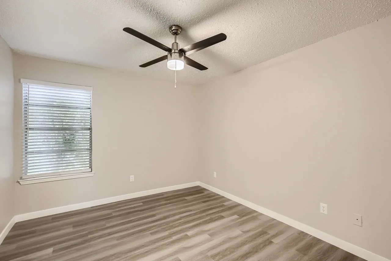 Bedroom, wood-style plank flooring, four-blade ceiling fan, window with blinds