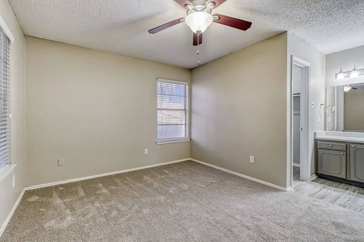 Primary bedroom, carpet flooring, ceiling fan with light fixture, single window with blinds, ensuite bathroom visible