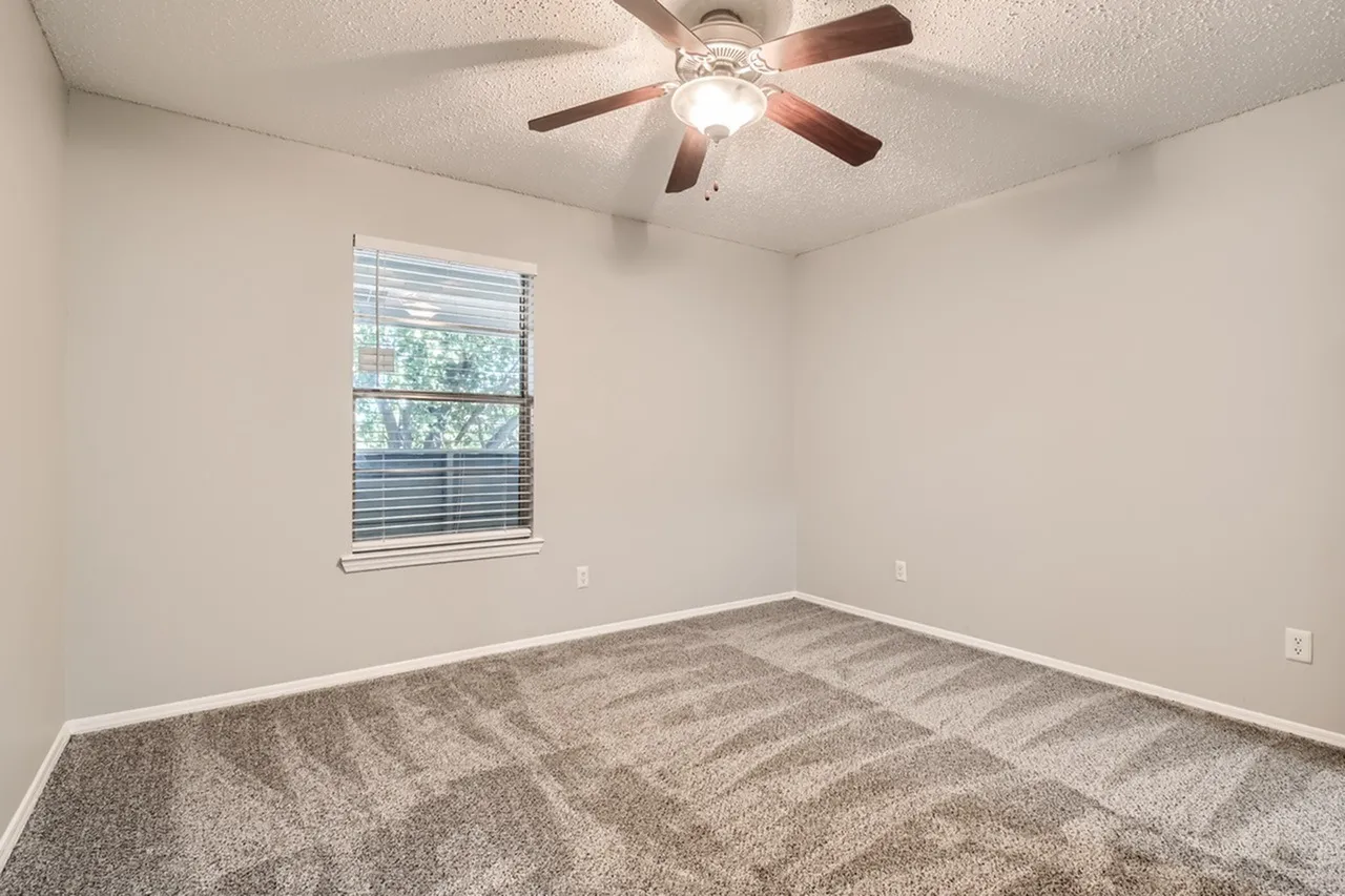Bedroom, gray patterned carpet, ceiling fan with light, window with blinds