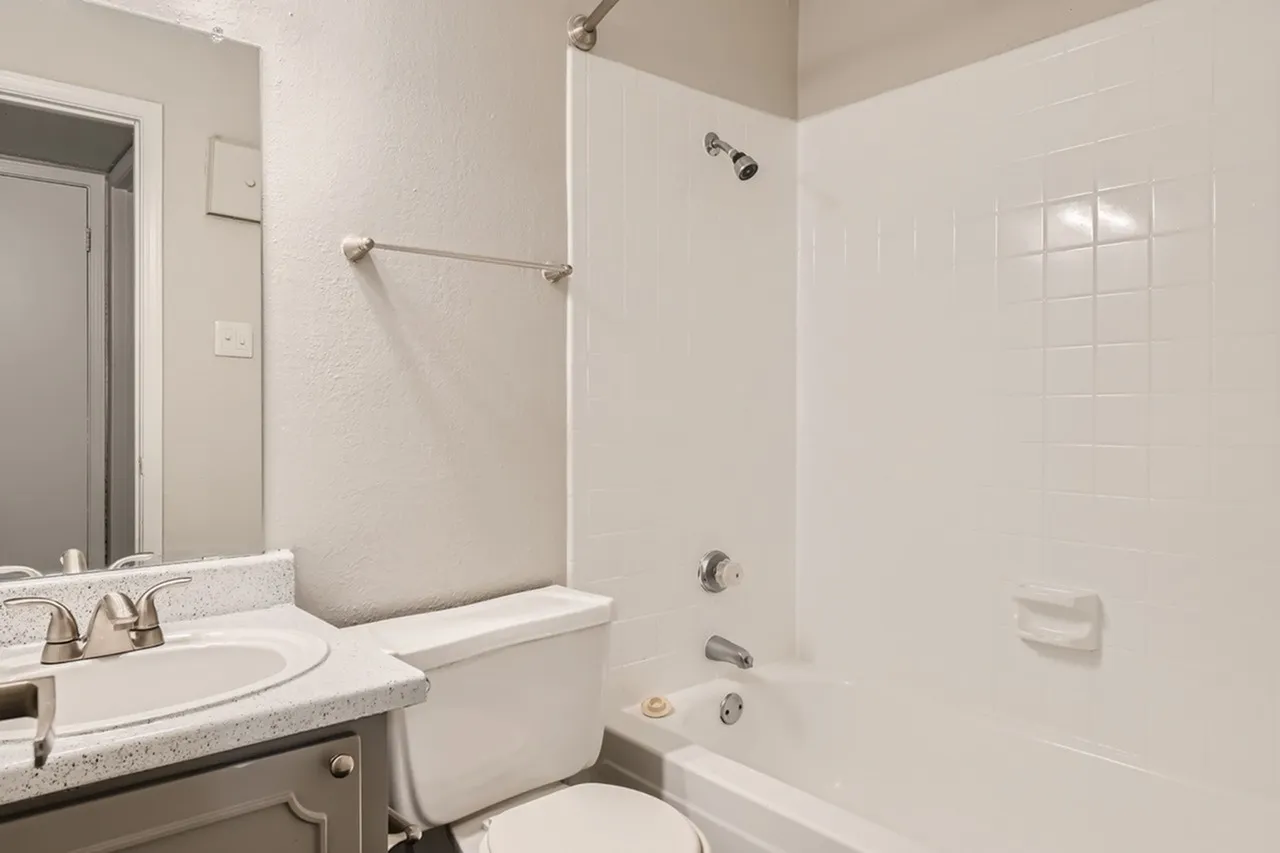 Primary bathroom, quartz countertops, white tile walls, glass shower enclosure