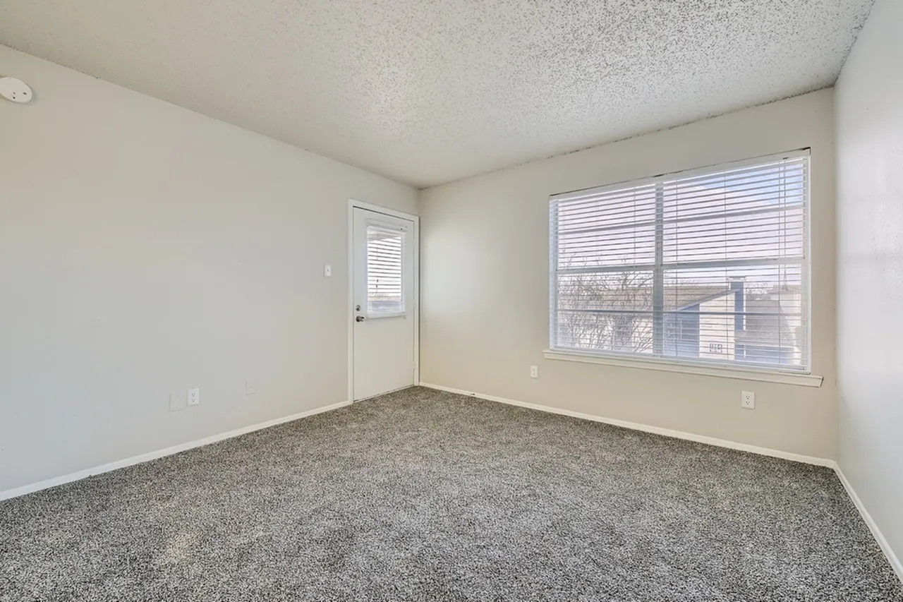 Bedroom, gray carpet flooring, large dual windows, exit door