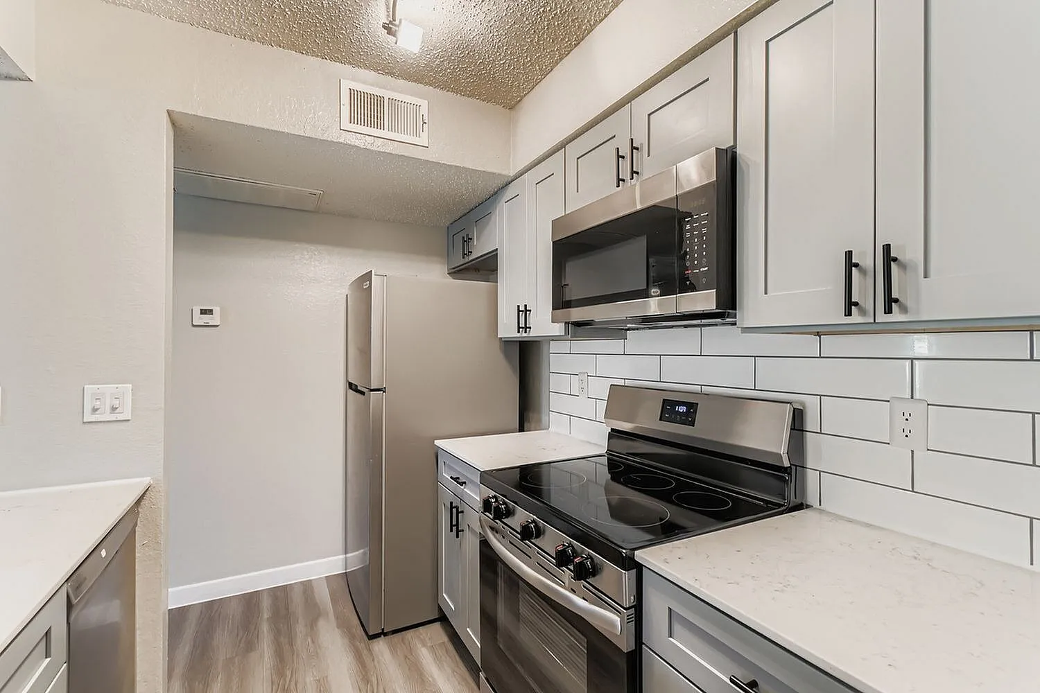 Kitchen, white shaker cabinetry, stainless steel appliances, quartz countertops, subway tile backsplash, wood-style plank flooring