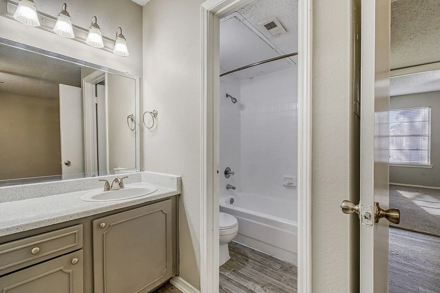 Primary bathroom, single vanity with taupe cabinetry, quartz countertop, illuminated mirror