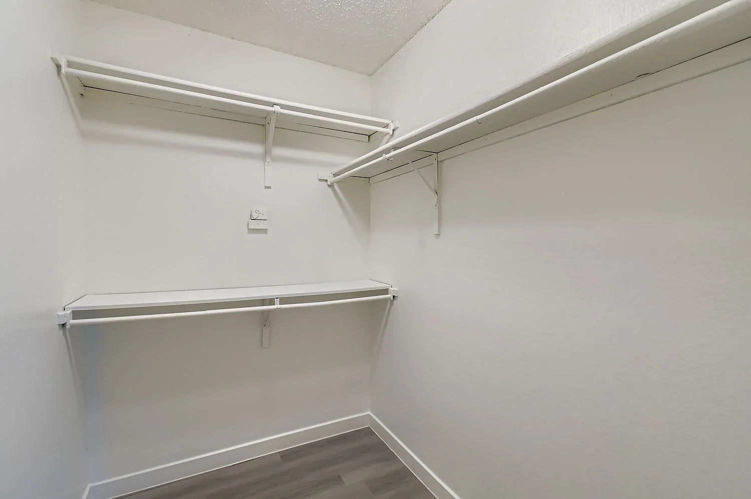 Closet, metal shelving, hanging rods, white walls