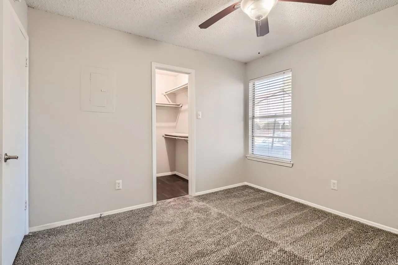 Bedroom, gray carpet flooring, ceiling fan, window with blinds, walk-in closet