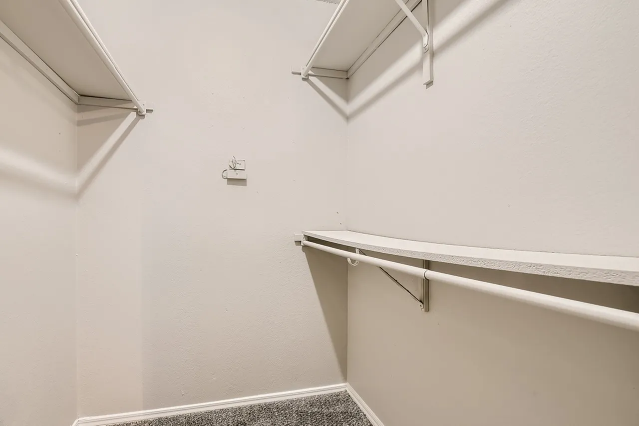 Walk-in closet, shelving with hanging rod, recessed lighting, white walls