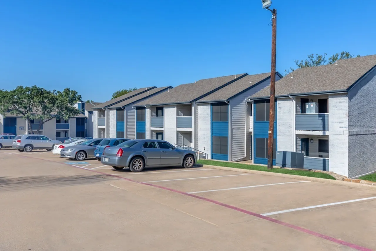 Multi-unit apartment complex, blue accent doors, brick and siding exterior, parking area