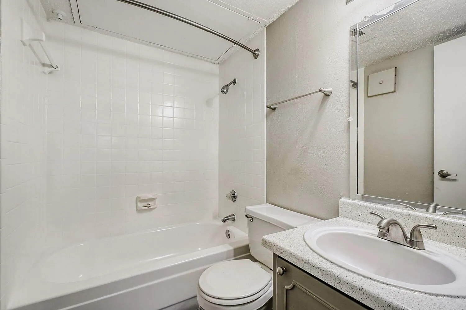 Bathroom, white subway tile shower surround, gray quartz countertops, oval sink, framed mirror
