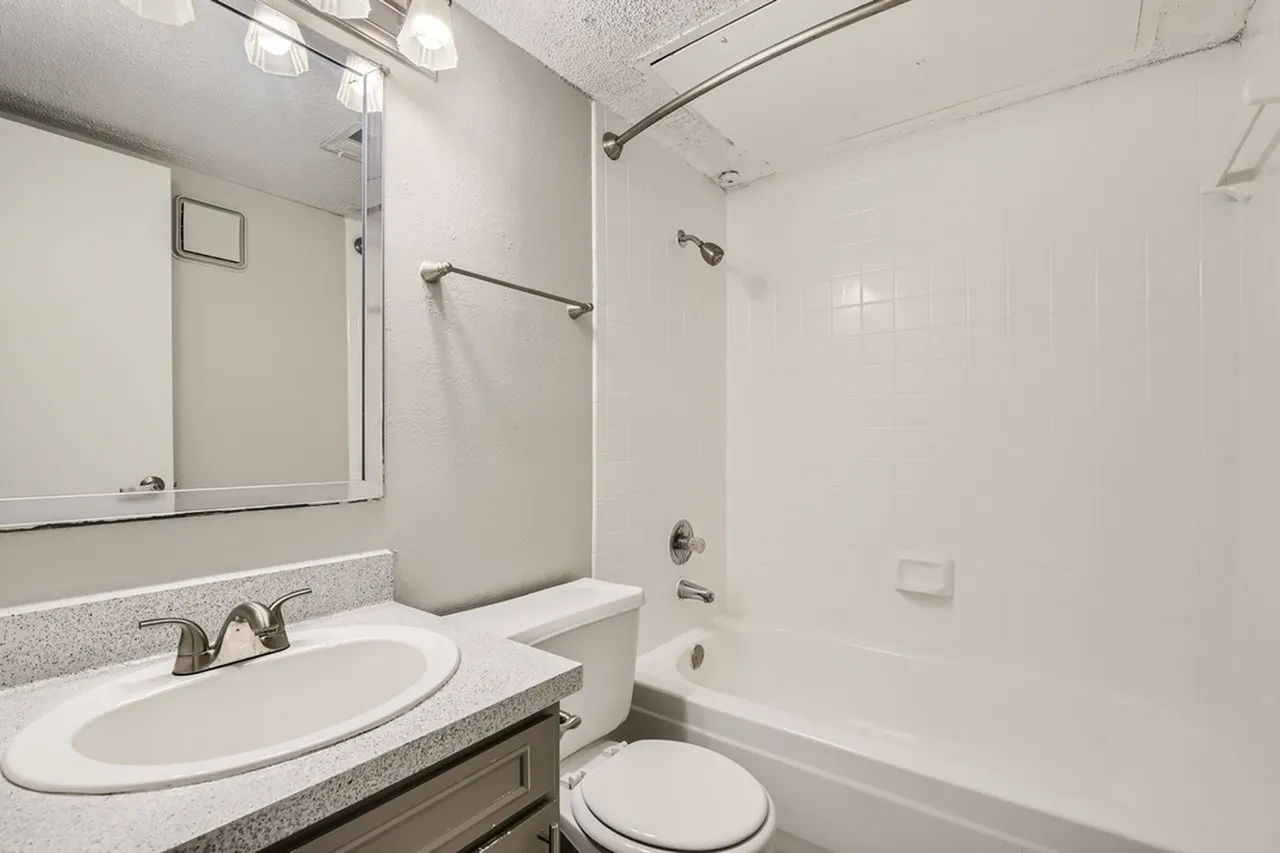 Bathroom, white vanity with round sink, gray countertop, large mirror, white tile shower