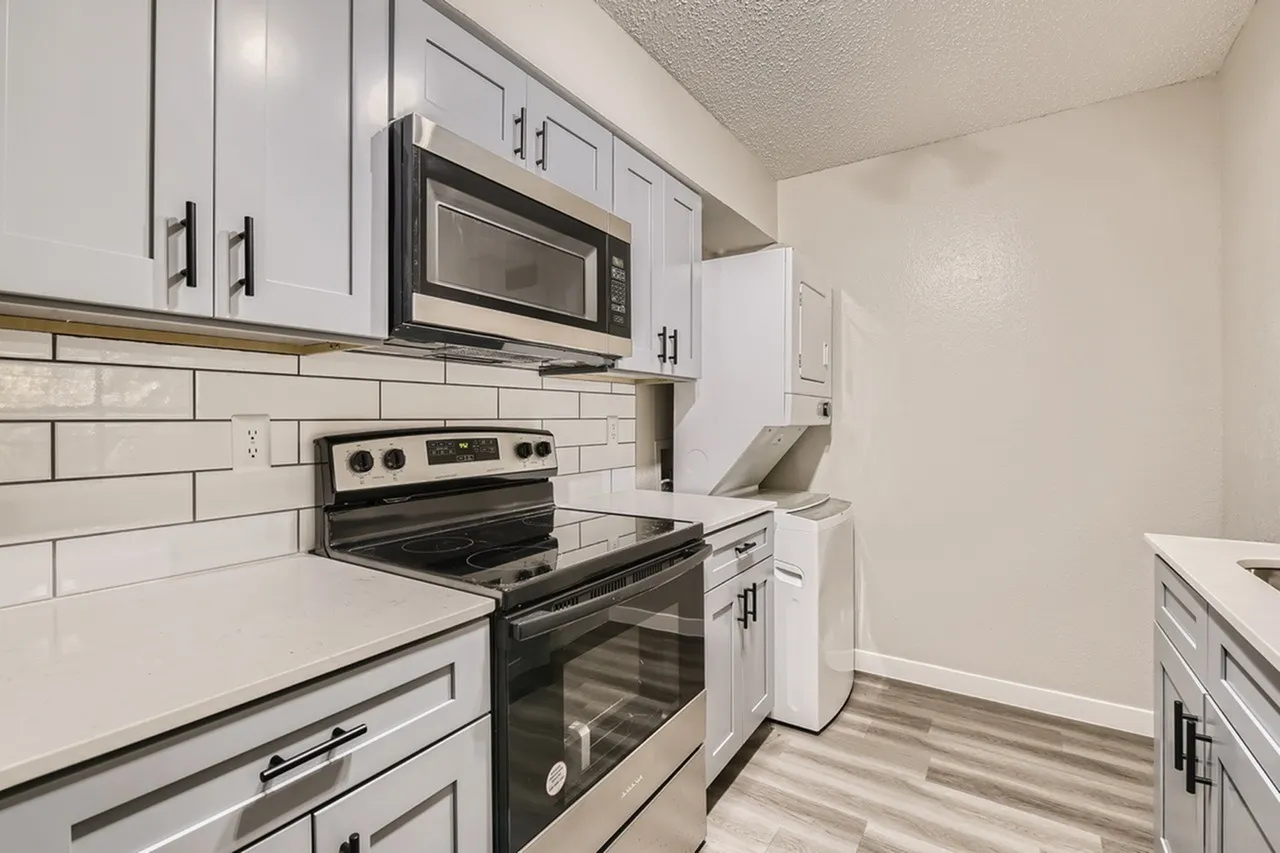 Kitchen, white shaker cabinetry, quartz countertops, stainless steel appliances, white subway tile backsplash, wood-style plank flooring