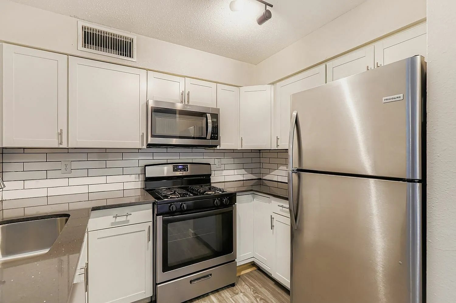 Kitchen, white shaker cabinetry, subway tile backsplash, stainless steel appliances, wood-style plank flooring